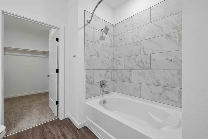 A1 one-bedroom bathroom at Garrett Fillmore with a tiled tub and shower and an adjoining walk-in closet.