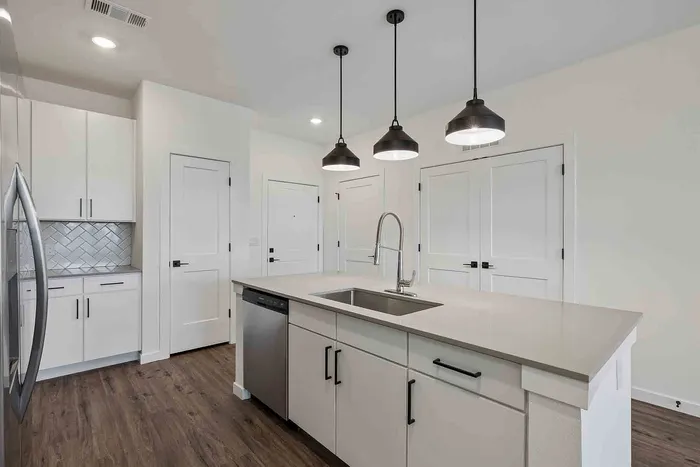 B1 two-bedroom kitchen at Garrett Fillmore with a center island, undermount sink, pendant lighting, and stainless dishwasher.
