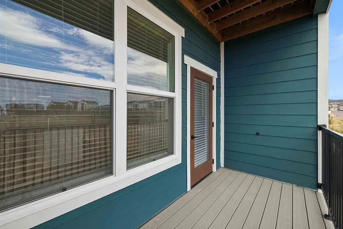 Covered private balcony on the C1 three-bedroom at Garrett Fillmore with composite decking and a metal railing.