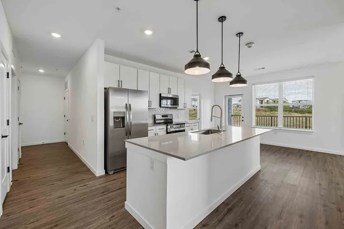 C1 three-bedroom kitchen at Garrett Fillmore with a long center island, side-by-side stainless refrigerator, and electric range.