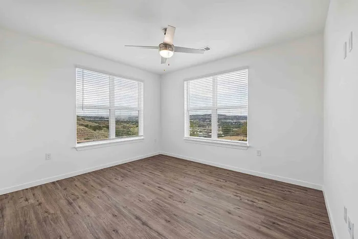 Living room in the C1 three-bedroom at Garrett Fillmore with two large windows overlooking open hillside and foothills.