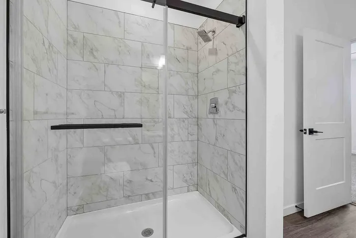 Walk-in shower in the C1 primary bathroom at Garrett Fillmore with marble-look tile and sliding glass doors.