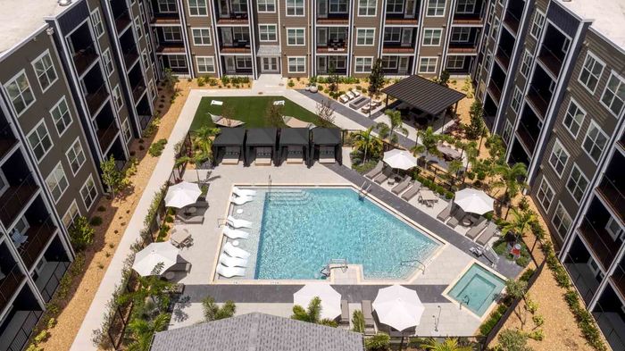 Overhead view of the Garrett Forum pool with in-water loungers on a sun shelf, a separate spa, four shaded cabanas, and umbrella seating