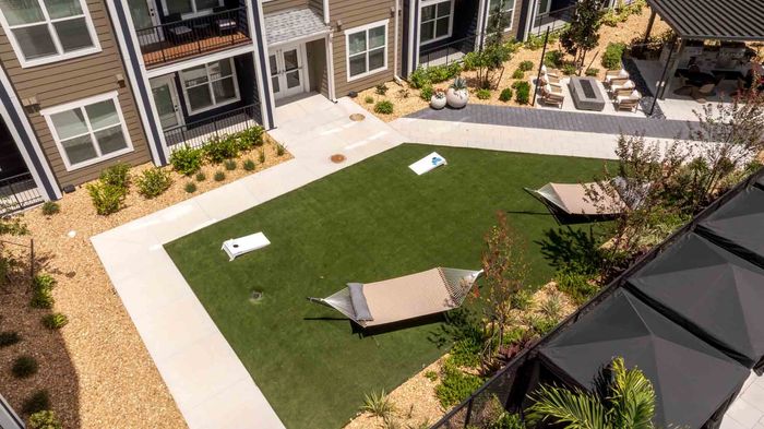 lawn in the Garrett Forum courtyard with two hammocks and a cornhole set