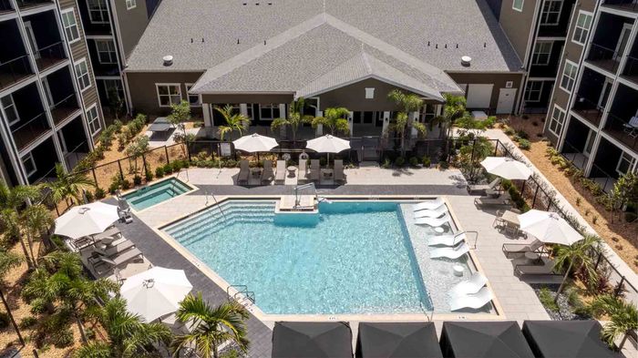 Aerial view of the Garrett Forum pool, spa, and sundeck with lounge chairs and umbrellas beside the clubhouse