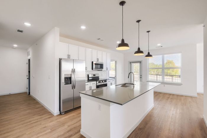 C1 three-bedroom kitchen at Garrett North Powers with island sink, black pendant lights, and stainless steel appliances