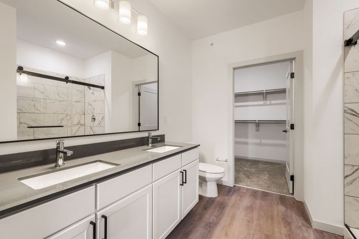 B3 primary bathroom at Garrett North Powers with a double vanity, tiled glass-door shower, and walk-in closet