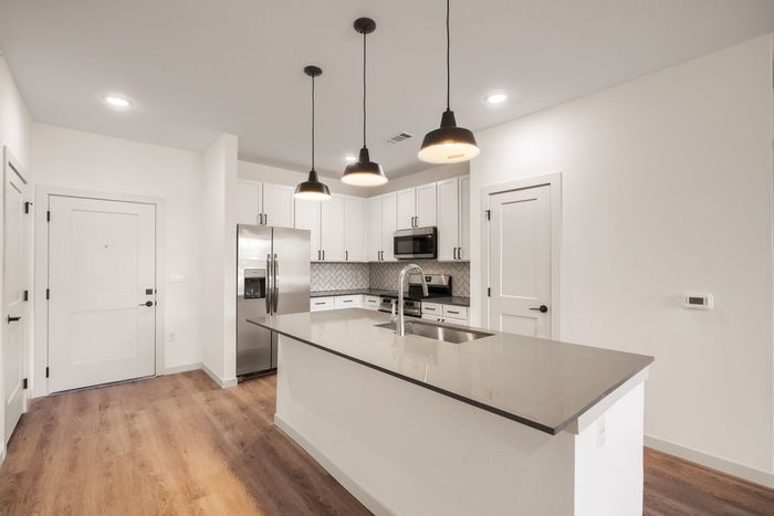 B1 two-bedroom kitchen at Garrett North Powers with island, pendant lights, and white herringbone tile backsplash