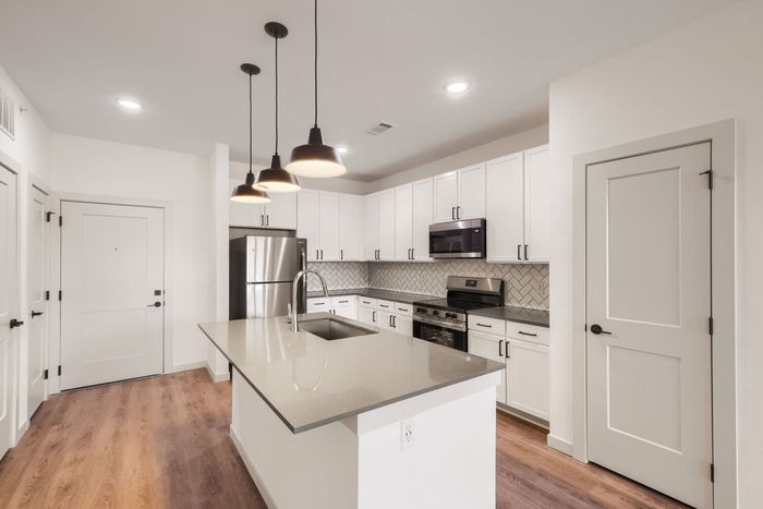 A1 one-bedroom kitchen at Garrett North Powers with island sink, three pendant lights, and stainless steel appliances