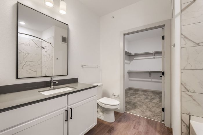 A1 one-bedroom bathroom at Garrett North Powers with a gray vanity top, black-framed mirror, and attached walk-in closet