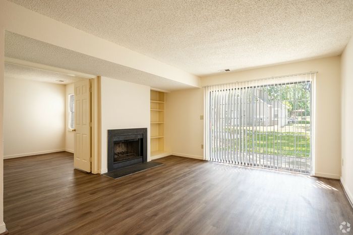 Inviting living room featuring natural light, hardwood floors, a cozy fireplace, and sliding glass doors opening to a garden view.