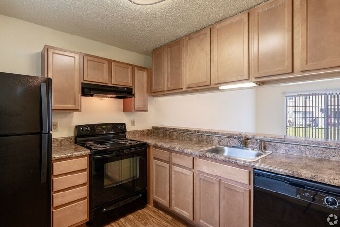 Modern kitchen with sleek black appliances, wooden cabinetry, and a granite countertop.