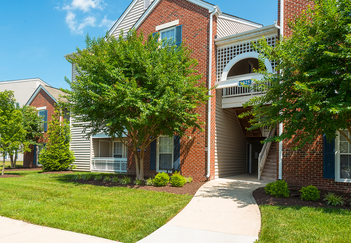 Charming red brick apartment with lush greenery and inviting entrance in a serene neighborhood.