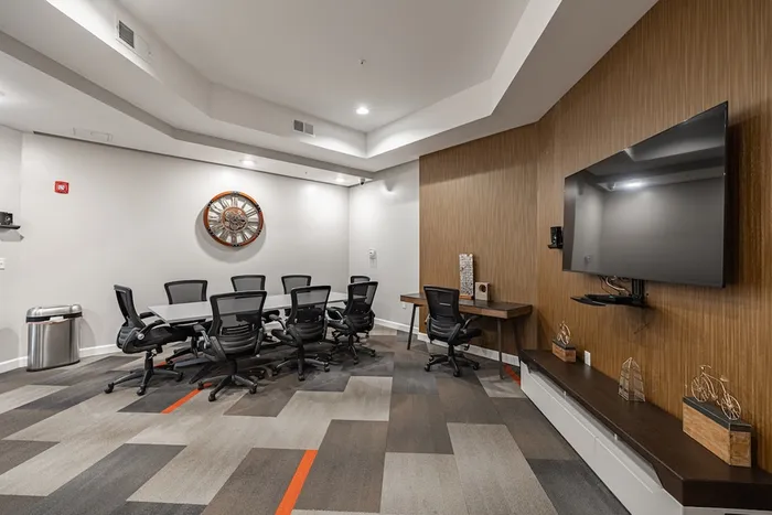 Modern conference room with sleek black office chairs, a large wall-mounted TV, and stylish decor, perfect for productive meetings and presentations.