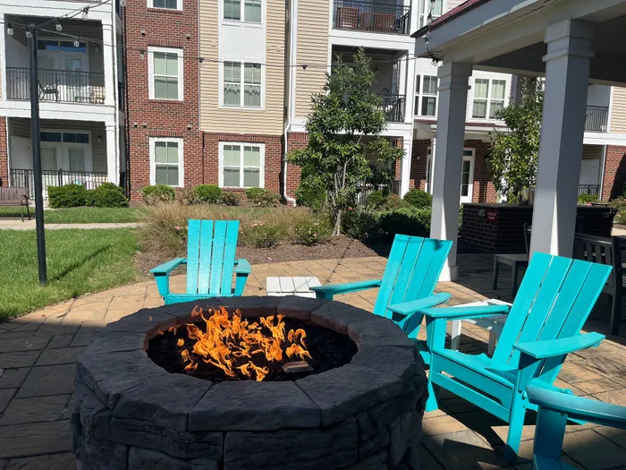 Charming apartment patio with a cozy fire pit surrounded by vibrant turquoise chairs, perfect for relaxing and enjoying the outdoors.
