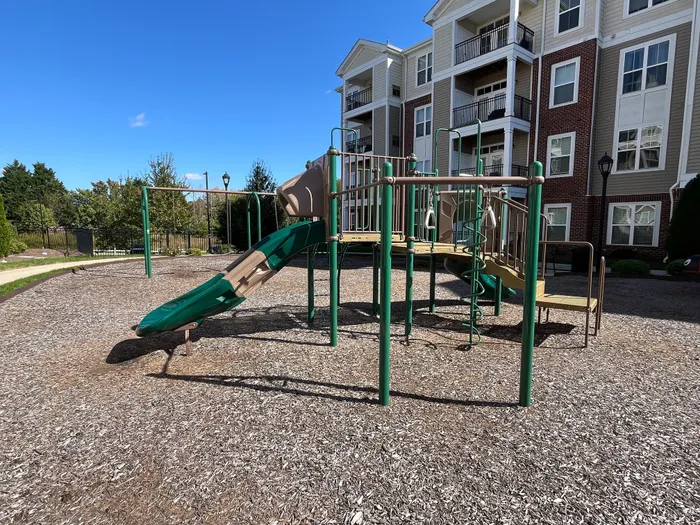 Inviting apartment playground with modern slides and climbing structures, set against a backdrop of charming multi-story buildings in a serene neighborhood.