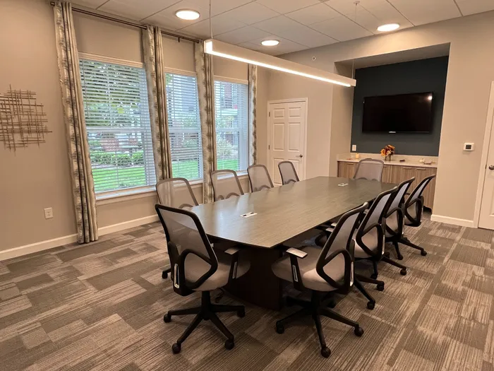 Elegant conference room with a modern table, sleek chairs, and large windows offering natural light, creating an inspiring workspace.
