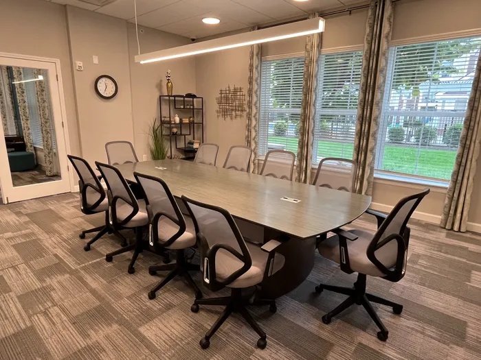 Elegant conference room with a modern oval table, sleek chairs, and large windows offering scenic garden views.
