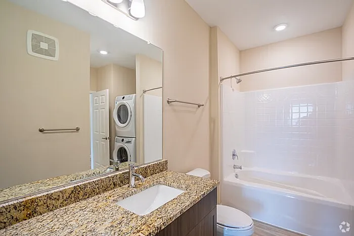 Elegant bathroom with granite countertops, spacious tub, and in-unit washer and dryer for modern convenience.