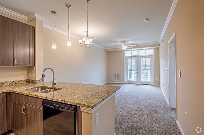 Inviting modern apartment with elegant kitchen island, stylish pendant lighting, and open-concept living space leading to a bright balcony.