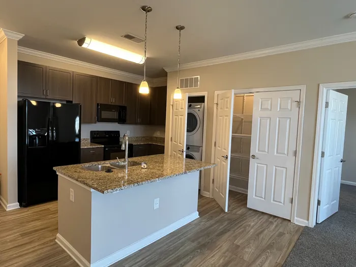 Chic apartment kitchen with granite countertops, modern appliances, and elegant wood cabinetry, perfect for culinary enthusiasts.