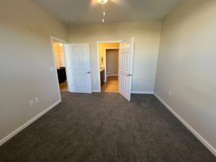 Inviting bedroom with plush carpet, neutral walls, and ample natural light, leading to an ensuite bathroom.