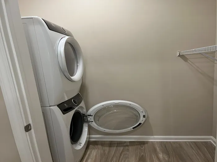 Modern laundry area featuring a sleek stacked washer and dryer with a spacious folding area, perfect for efficient home living.