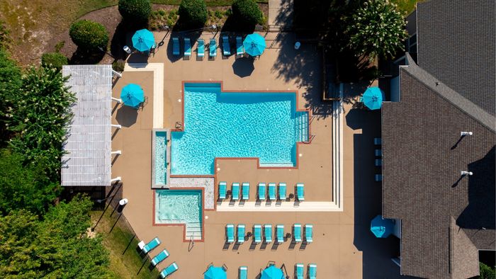 Inviting aerial view of a vibrant, resort-style pool with turquoise loungers and umbrellas, perfect for relaxation and leisure.