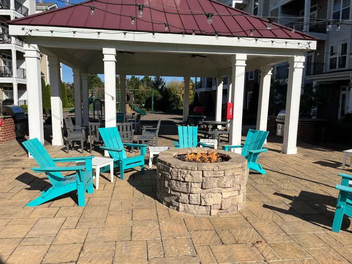 Charming outdoor pavilion with vibrant turquoise chairs surrounding a cozy fire pit, perfect for social gatherings and relaxation.