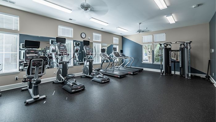 Modern fitness center with state-of-the-art equipment, including treadmills and strength machines, in a well-lit and spacious room.
