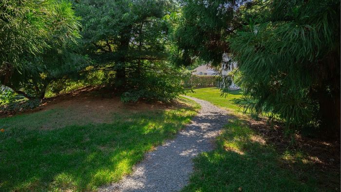 Inviting garden pathway surrounded by lush greenery leading to a serene residential area.