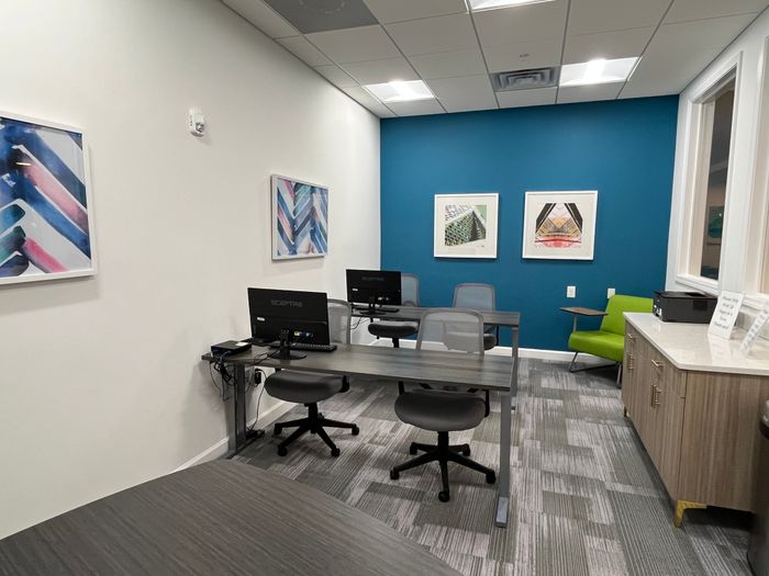 Modern workspace with sleek desks and computers, accented by vibrant wall art and a stylish blue feature wall.