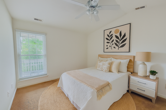 Elegant bedroom with natural light, featuring a cozy bed, stylish artwork, and modern decor accents.
