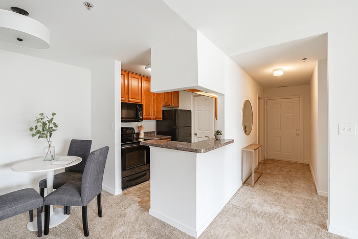 Contemporary apartment with open-concept kitchen featuring wooden cabinetry, a cozy dining nook, and a bright entrance hallway.