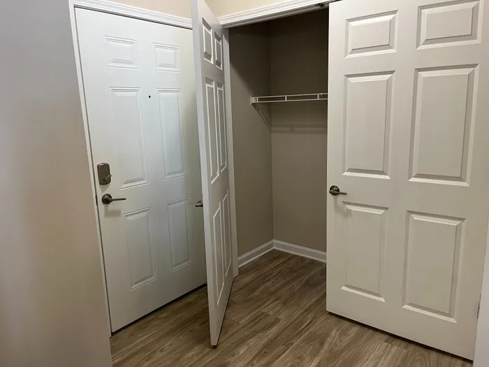Inviting apartment entryway featuring sleek wooden flooring and a spacious closet.