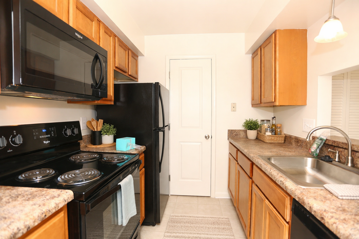 Charming kitchen with sleek black appliances, warm wood cabinetry, and beautiful granite countertops, creating a cozy and inviting ambiance.