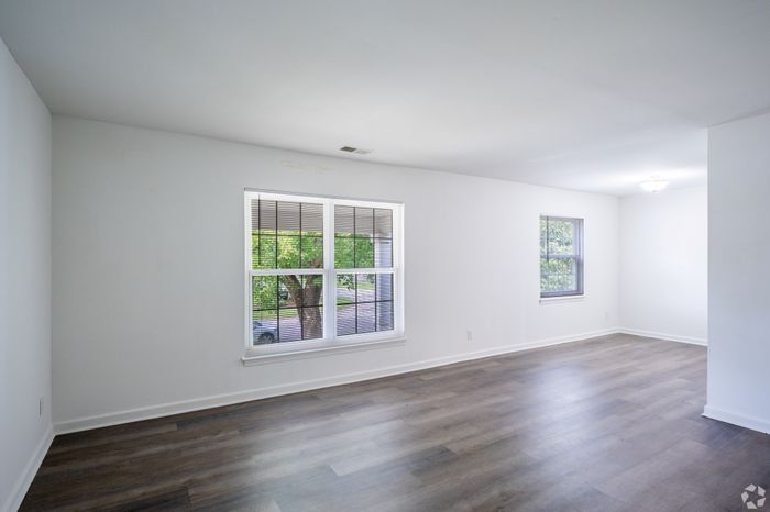 Bright and spacious living room with large windows and elegant hardwood flooring, perfect for modern living.