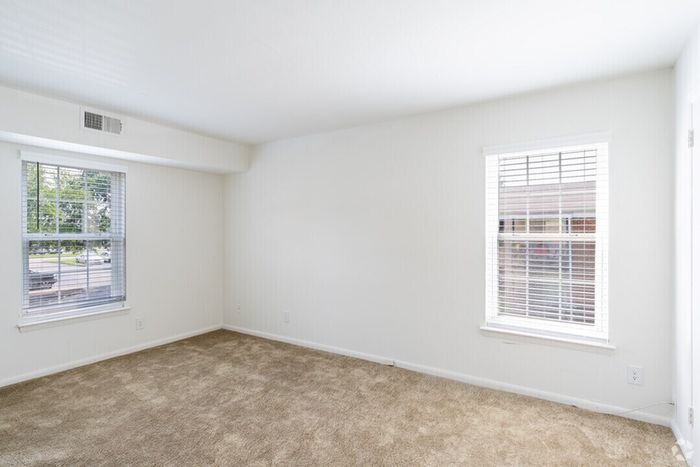 Bright and spacious carpeted room with large windows for natural light.