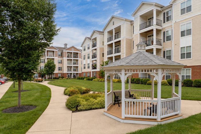 Charming apartment complex with lush green landscaping and a picturesque gazebo, offering a serene and inviting atmosphere.