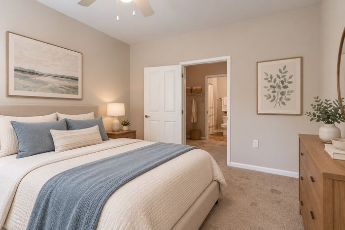 Inviting bedroom with elegant decor, featuring cozy bed with plush pillows, warm ambient lighting, and tasteful artwork, leading to an en-suite bathroom.