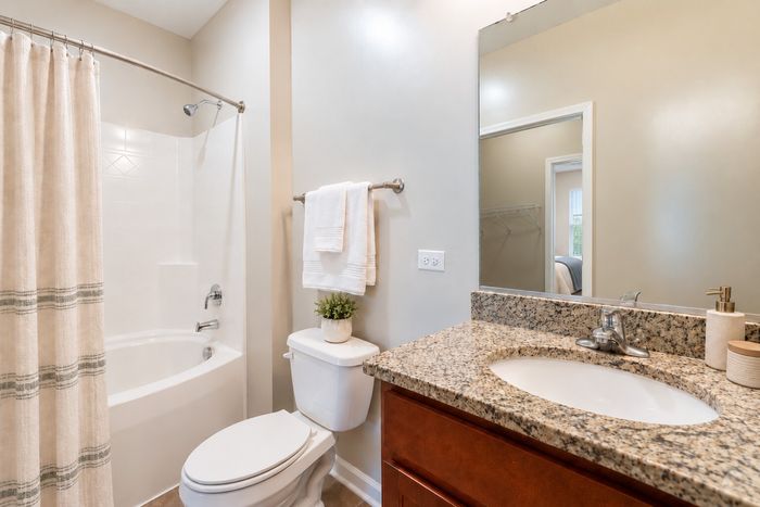 Modern bathroom with elegant marble countertop, sleek sink, and cozy bathtub with stylish curtain.