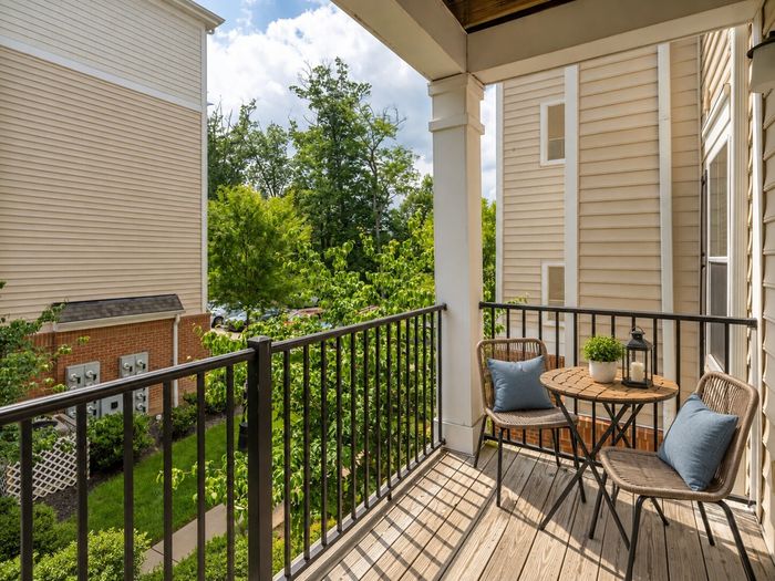 Charming private balcony with cozy seating, lush greenery views, and stylish decor for serene outdoor relaxation.