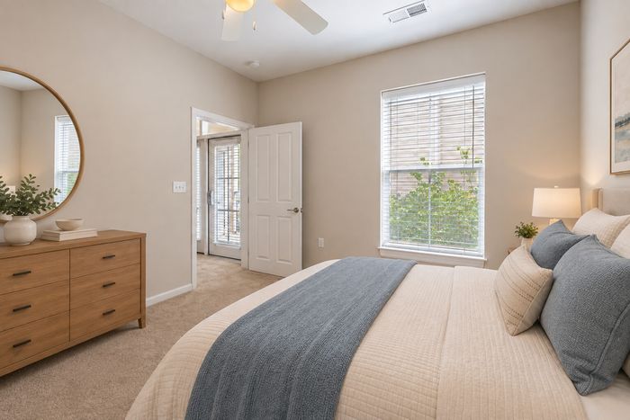Bright and inviting bedroom with a cozy bed, elegant decor, and abundant natural light from large windows.