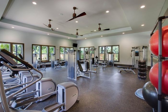 Photo of fitness center showing several elliptical machines, as well as 7 weight stations, and multiple free-weights and exercise balls.