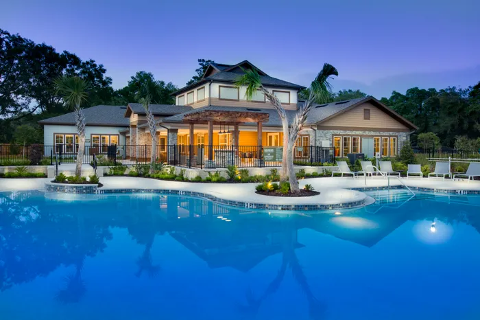 Photo overlooking swimming pool with outdoor seating, with the clubhouse in the backrgound.