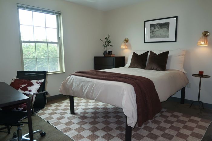 Inviting bedroom with a large window, cozy bedding, and chic decor, perfect for relaxation and comfort.