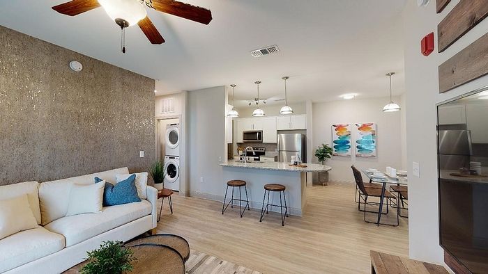 Modern open-concept living room with cozy seating, elegant kitchen island, stainless steel appliances, and stylish dining area.