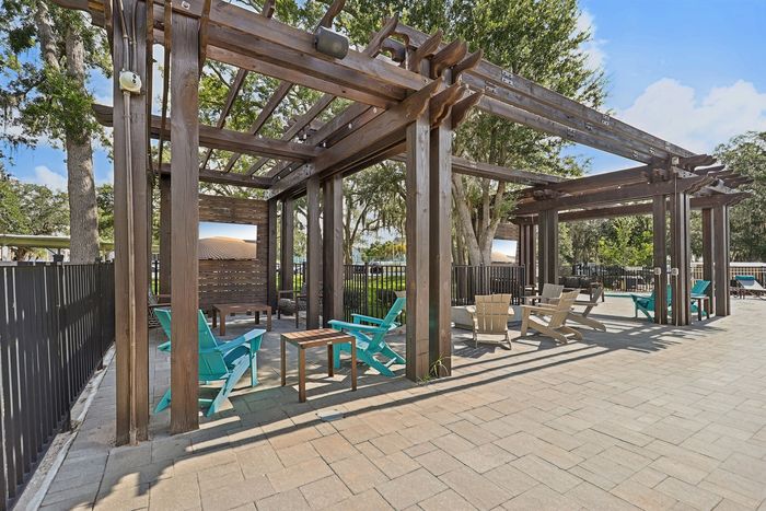 Charming outdoor patio with stylish wooden pergola, vibrant chairs, and lush greenery, perfect for relaxing and entertaining.