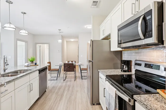 Modern kitchen with granite countertops, stainless steel appliances, and a stylish dining area with natural light.