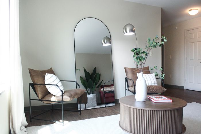 Chic living room with modern seating, large decorative mirror, and elegant lighting creating a cozy atmosphere.